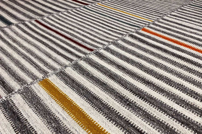 Close-up of the kilim weave pattern: gray stripes with yellow-orange and red accents