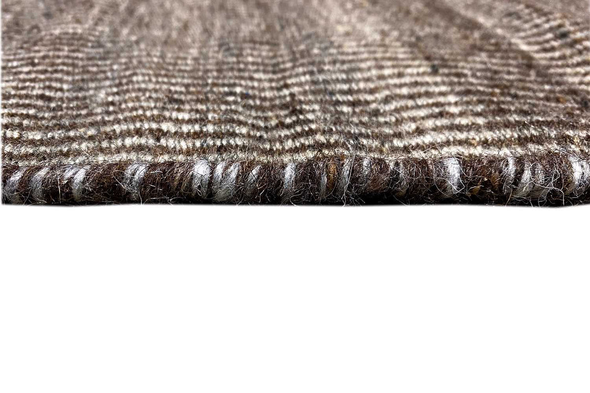 Carpet edge with braided trim, dark brown-black border, and fine woven texture