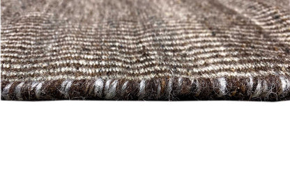 Carpet edge with braided trim, dark brown-black border, and fine woven texture