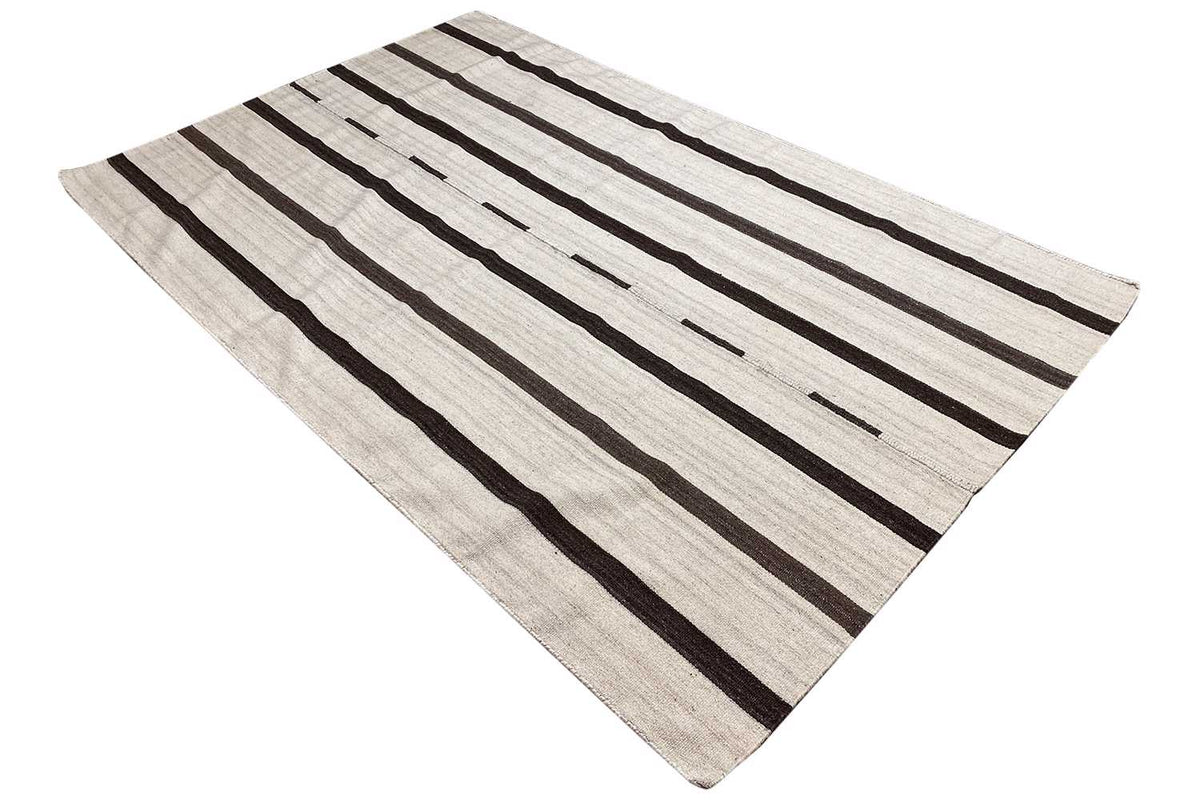 Kilim rug, diagonal view: light beige surface with black stripes and gaps.