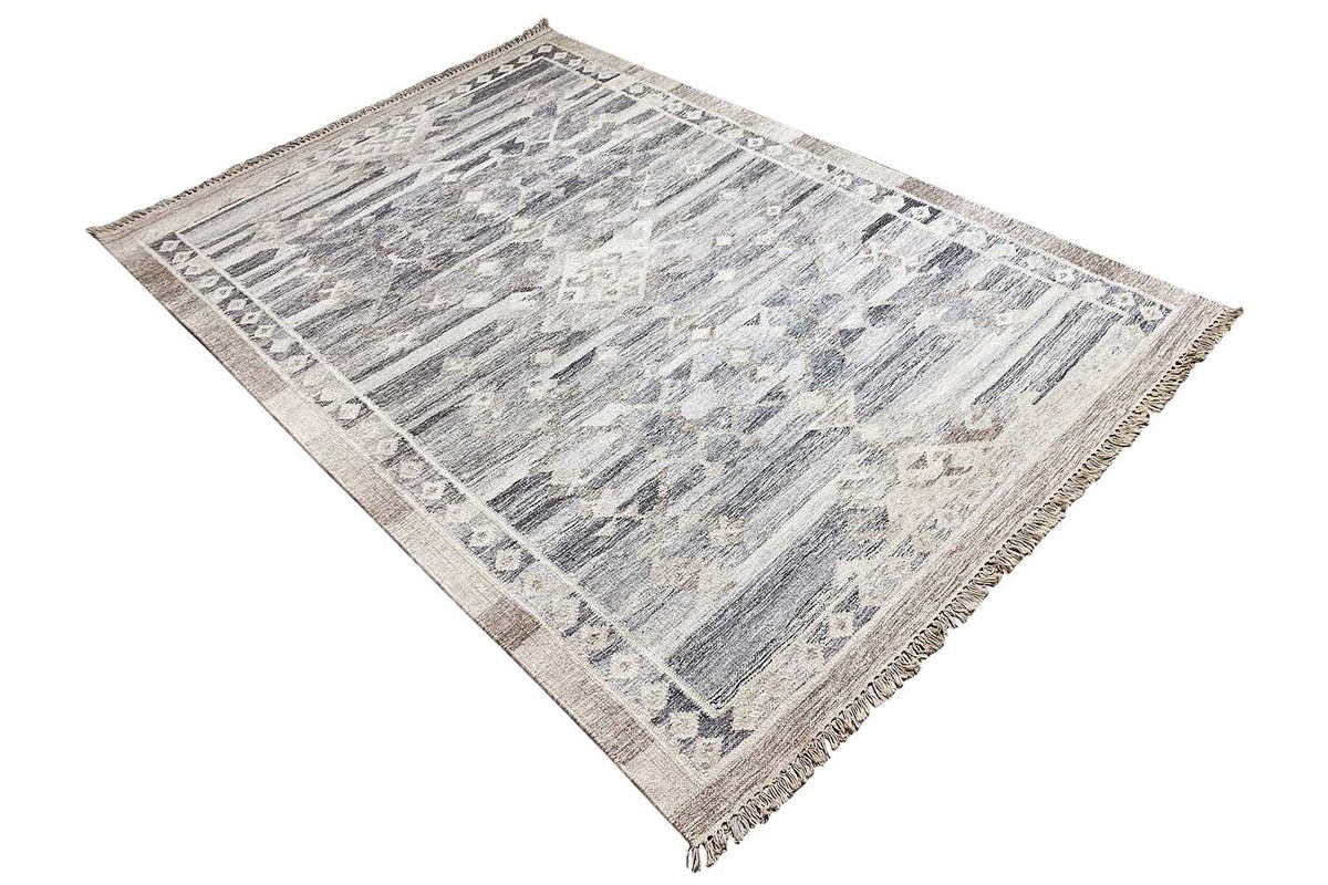 Kilim rug viewed diagonally, abstract blue-gray pattern on a light background, fringes