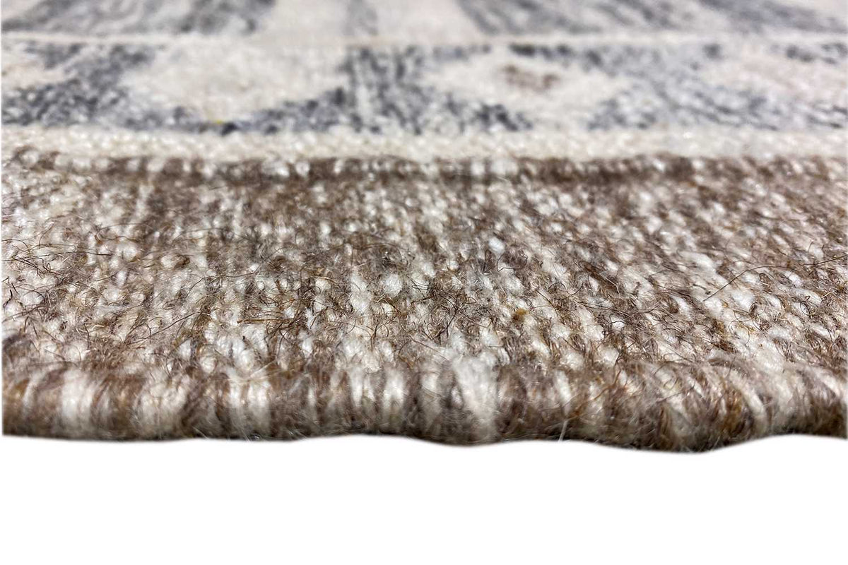 Close-up: kilim rug with dense fringe along the edge, blue-gray patterned surface