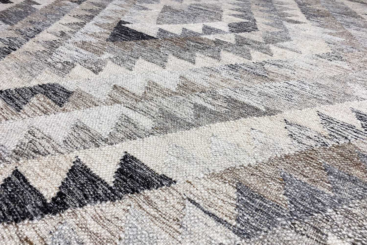 Kilim dhurrie detail shot, woven texture with a zigzag pattern in gray and beige