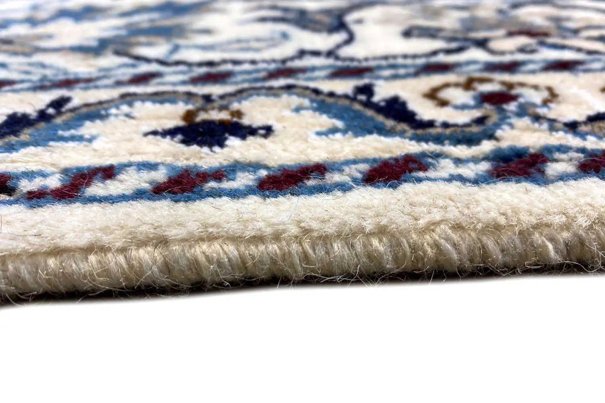 Close-up of the carpet edge: multicolored pile with blue-and-white patterns and a short selvedge.