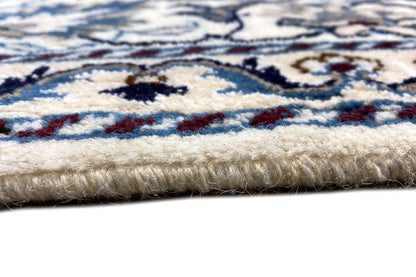 Close-up of the carpet edge: multicolored pile with blue-and-white patterns and a short selvedge.