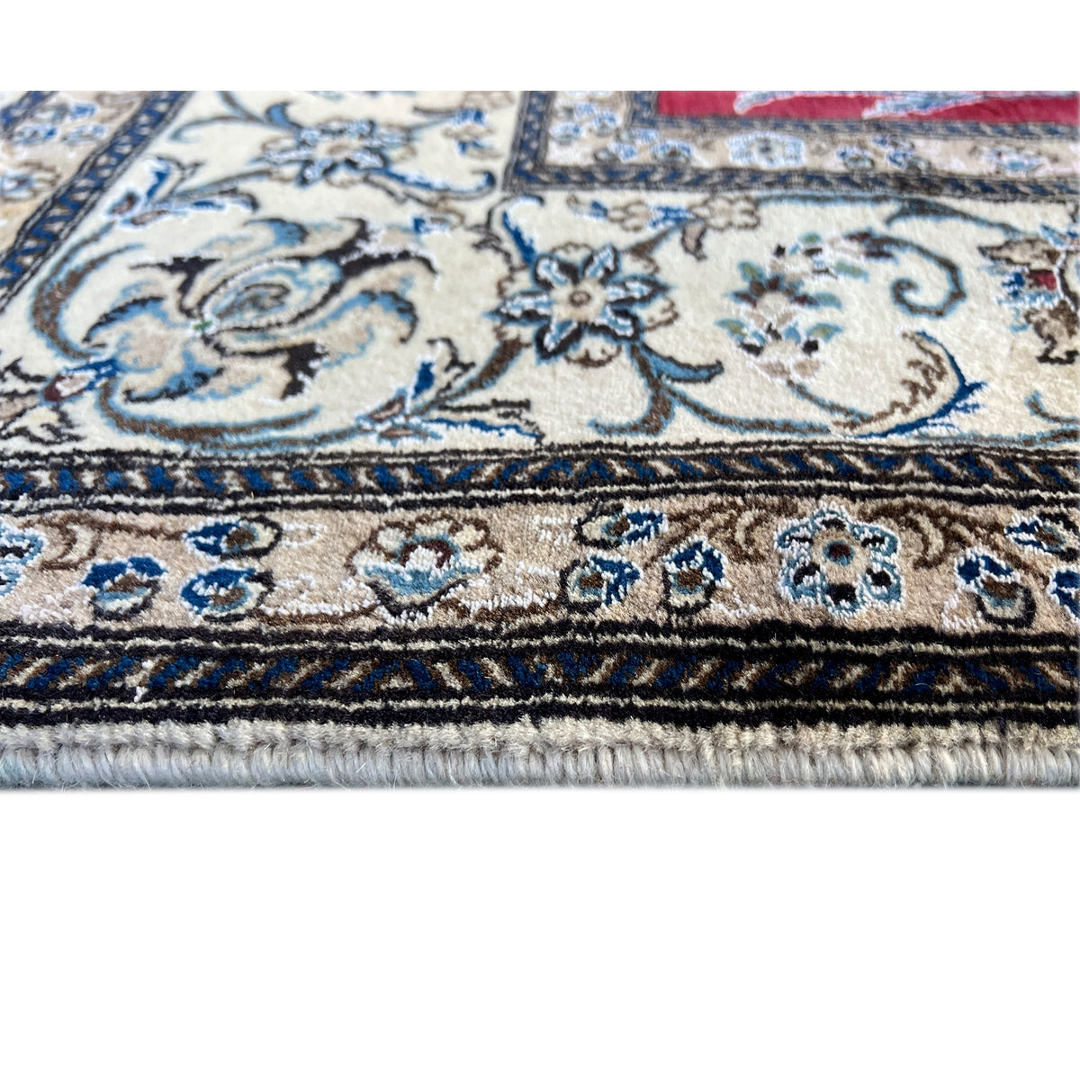Close-up of a carpet edge: ornamental stripe in blue, light background, and fringe along the edge