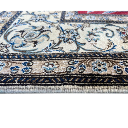 Close-up of a carpet edge: ornamental stripe in blue, light background, and fringe along the edge