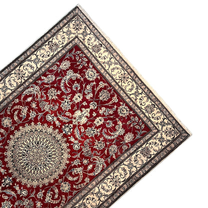 Top view: red Nain rug with fine white ornaments, a central medallion, and a corner border