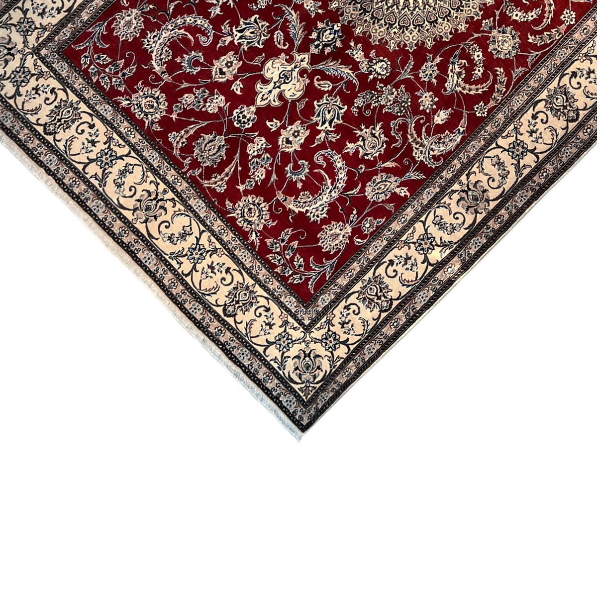 Nain wool rug at an angle: red field with detailed embellishments, surrounding cream-colored border