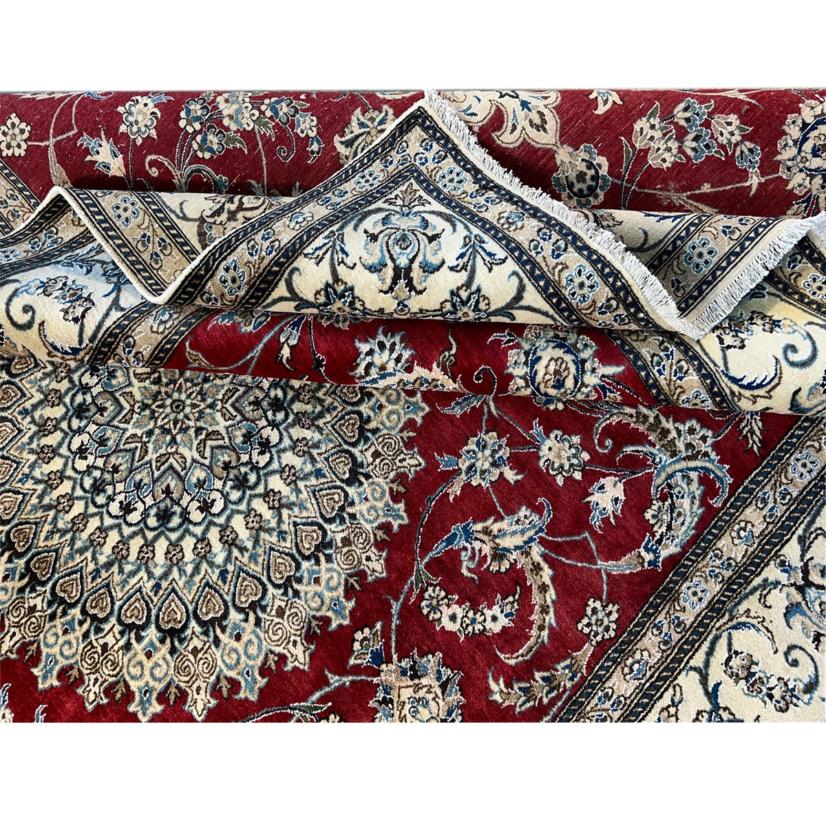 Close-up of a crumpled carpet surface: red pattern with an ornamental border, elaborately floral-crafted