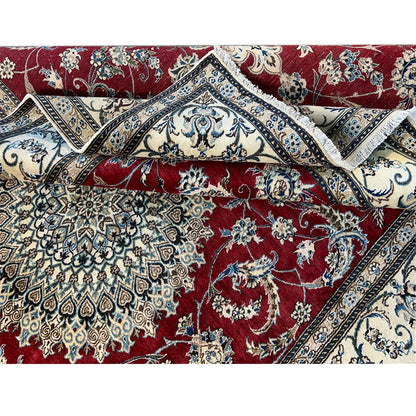 Close-up of a crumpled carpet surface: red pattern with an ornamental border, elaborately floral-crafted