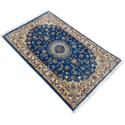 Blue Nain rug with a central medallion and floral ornaments, fringes along the edges.