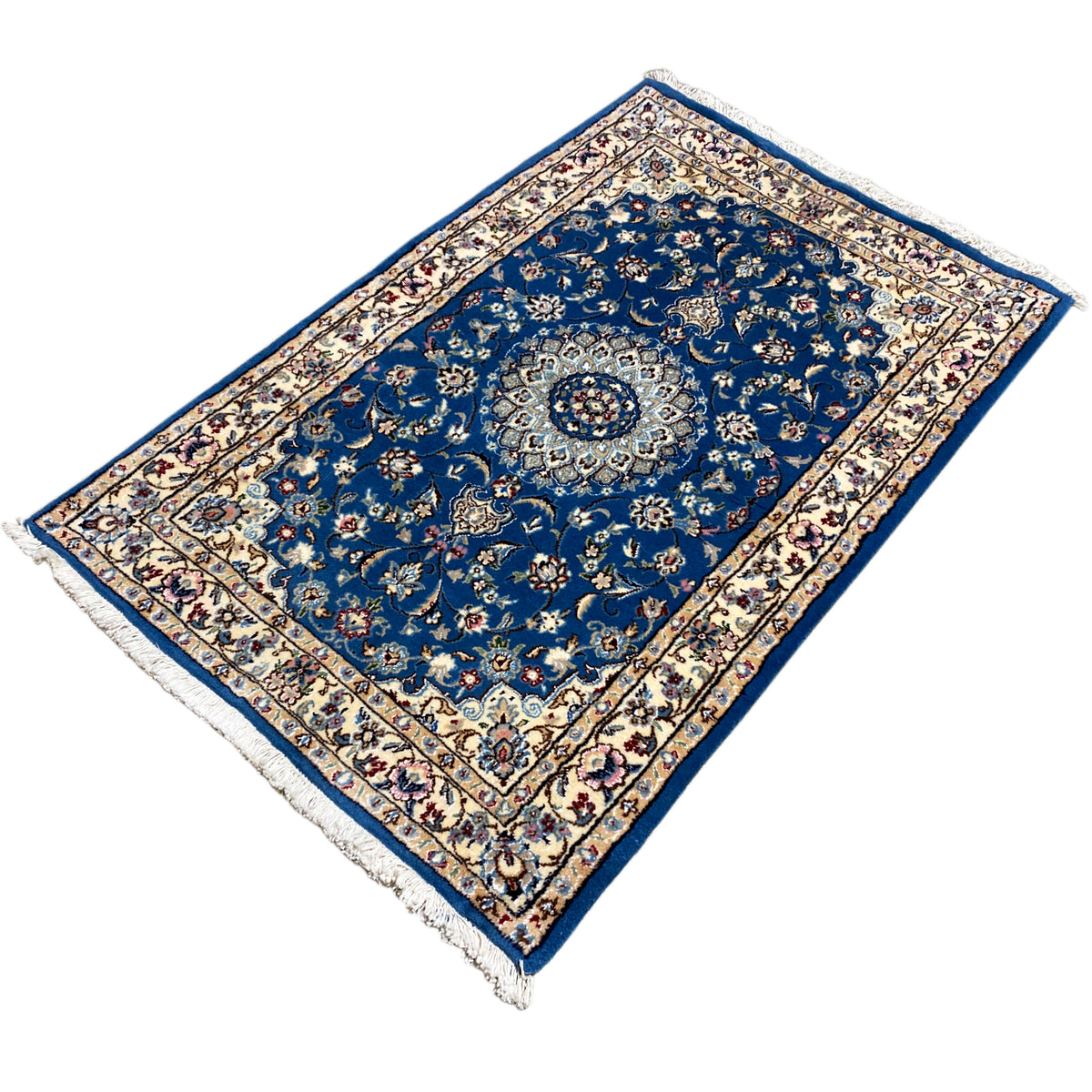 Blue Nain rug with medallion, border pattern and fringes, shown in three-quarter view.
