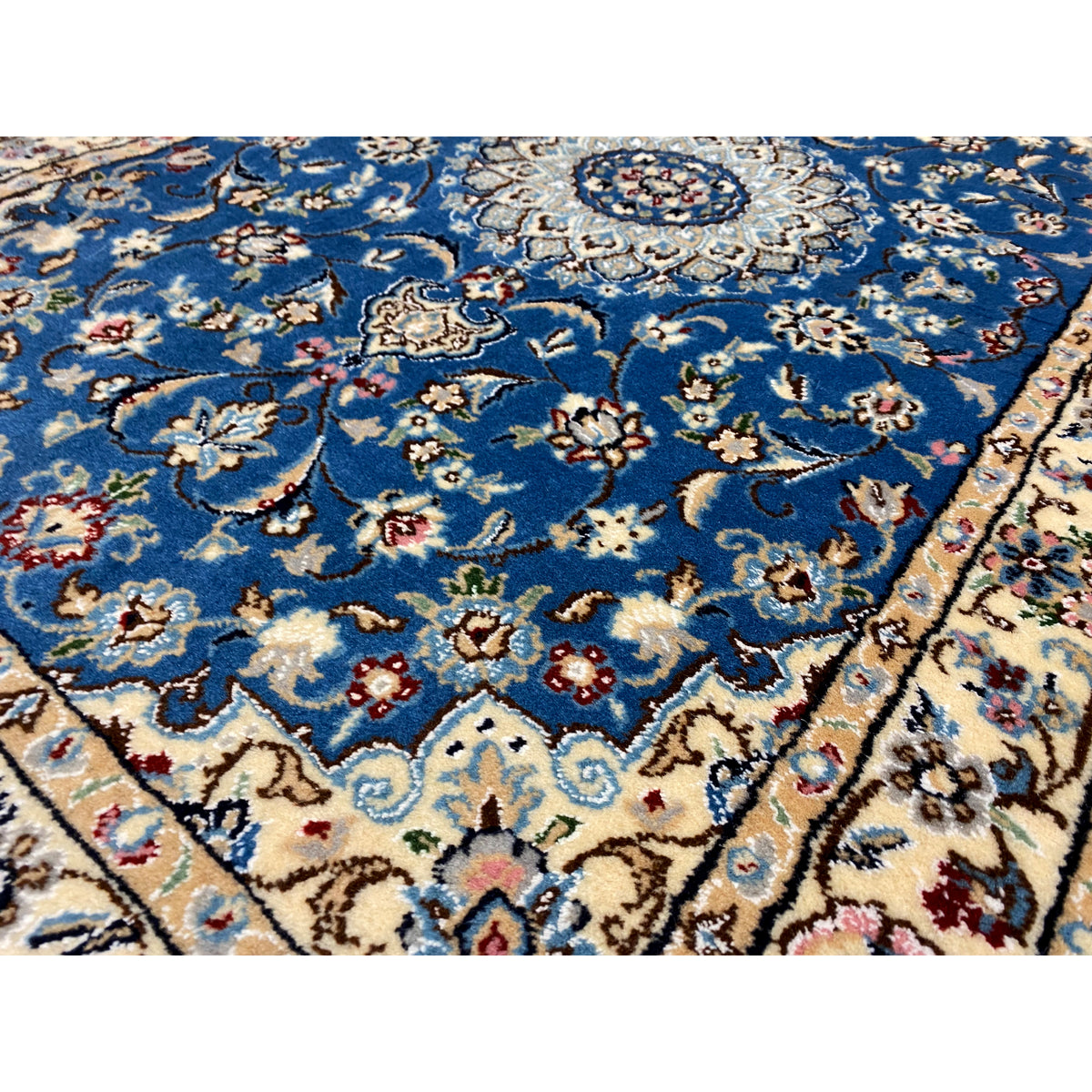 Close-up: Blue Nain rug with floral ornaments and a medallion in the center.