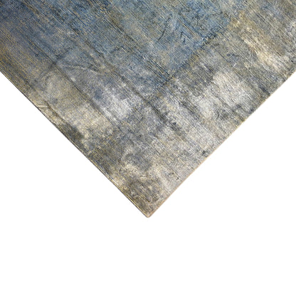 Corner of the rug with light gray-blue, mottled pattern and fine woven-like texture