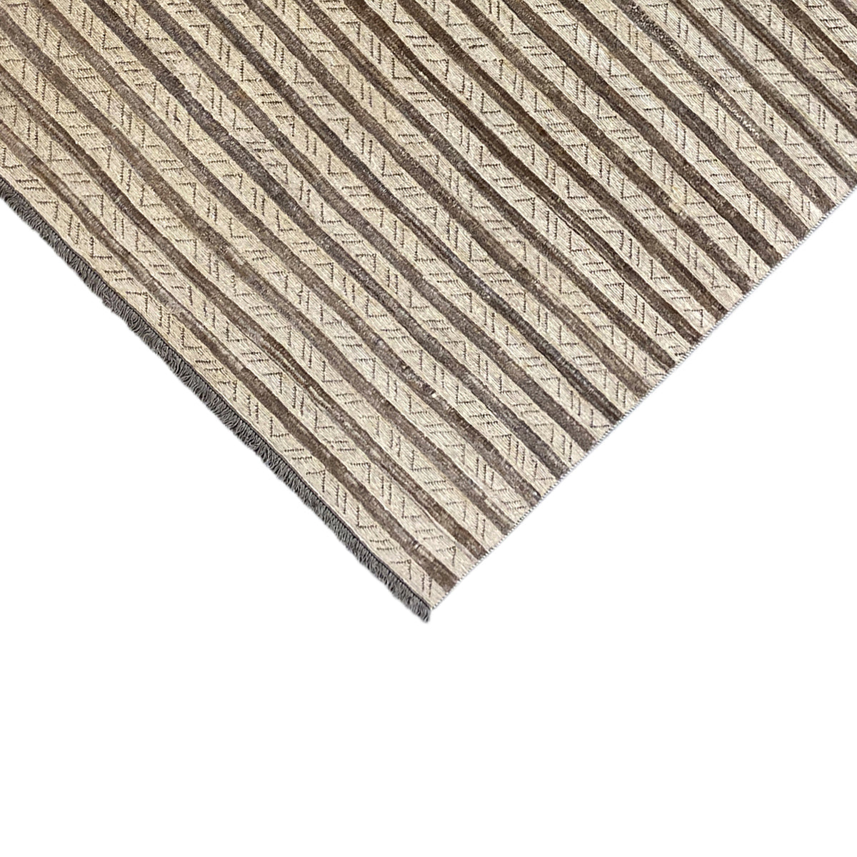 Rug corner in detail: striped pattern in beige and brown, side hem visible