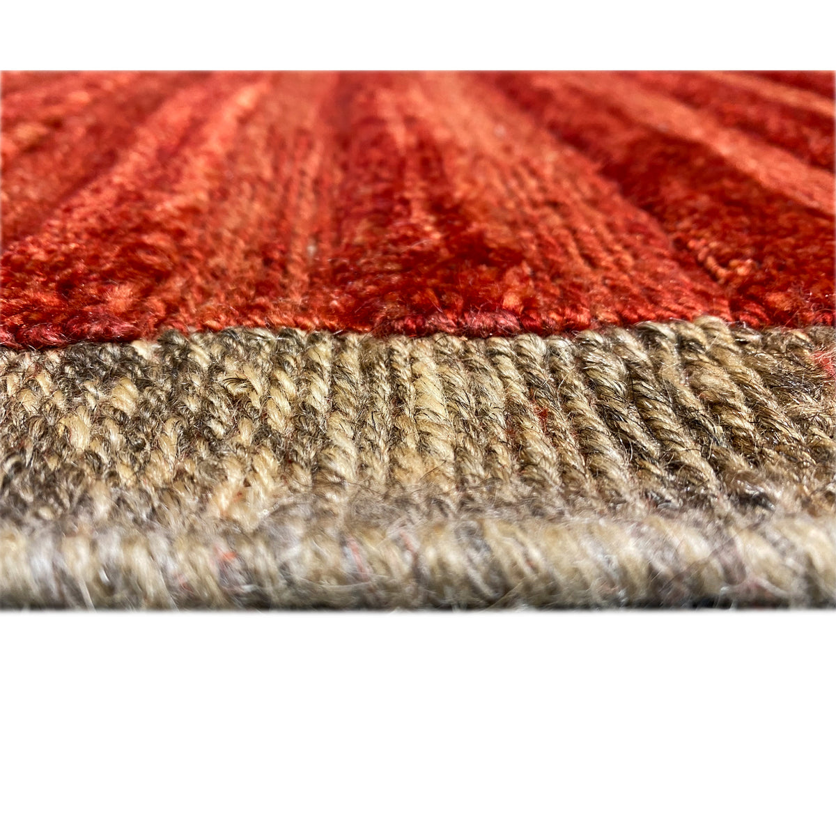 Close-up of a carpet edge with a beige fringe/hem finish beneath red stripes