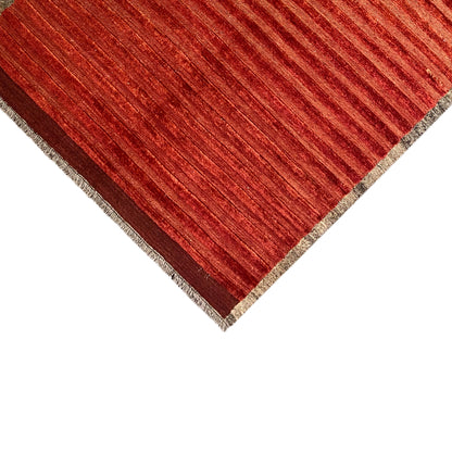 Corner of the rug with red stripes and a beige edge finish