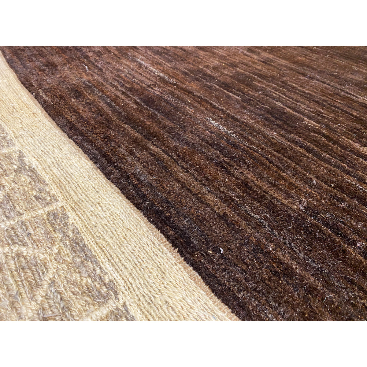 Close-up of dark brown carpet pile with beige fiber sections at the side edge