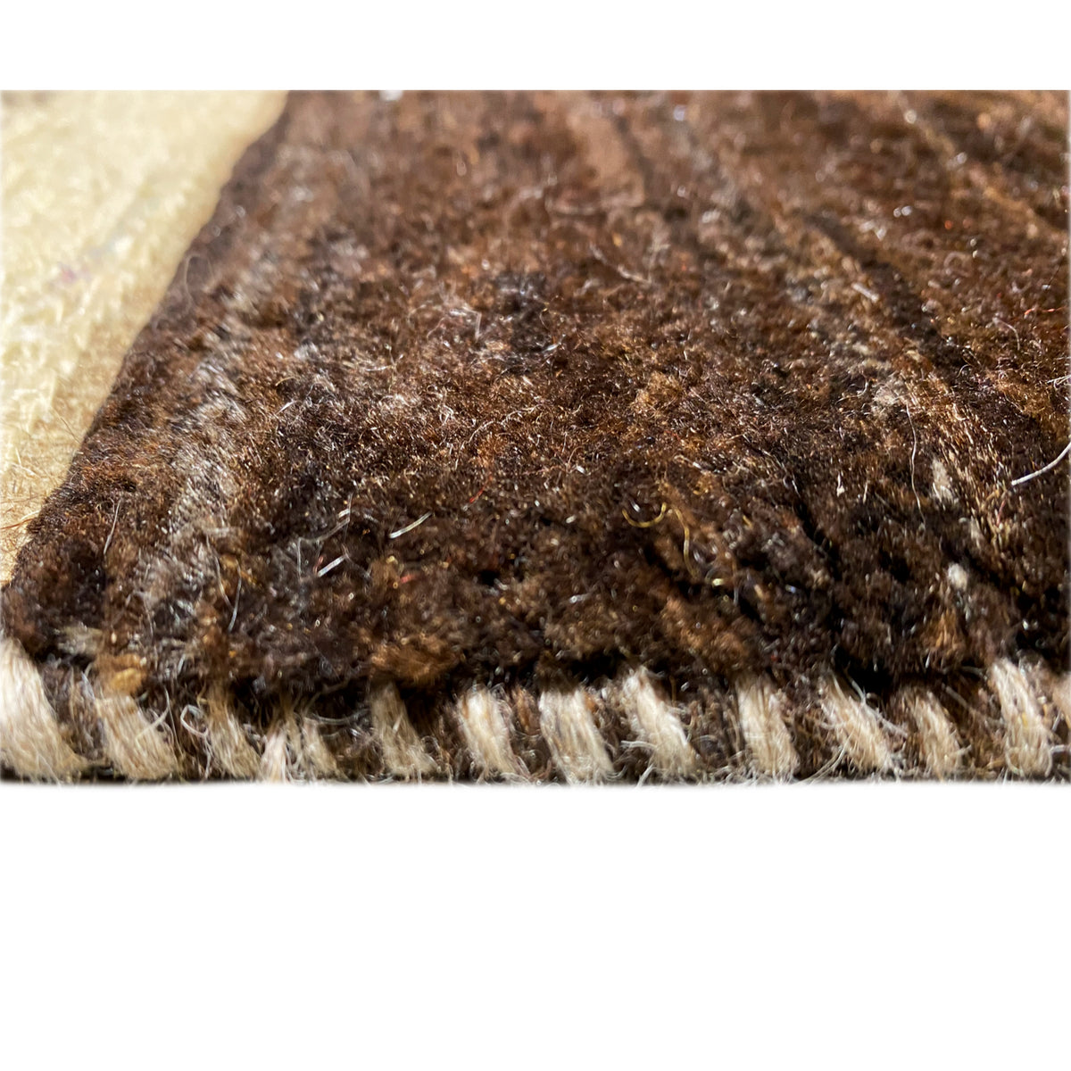 Close-up of dense brown pile texture with a beige edge and frayed border