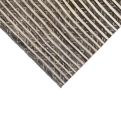 Close-up of a rug corner with a striped pattern and fringe, smooth border area
