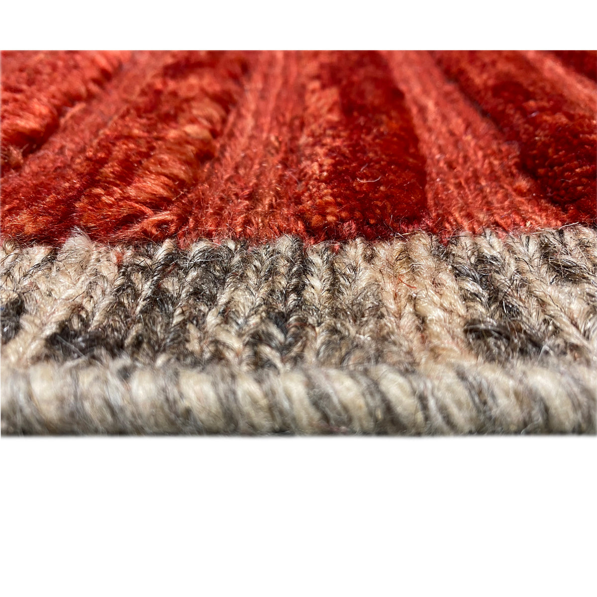 Close-up: carpet edge with beige and dark pile, with a red stripe pattern above it