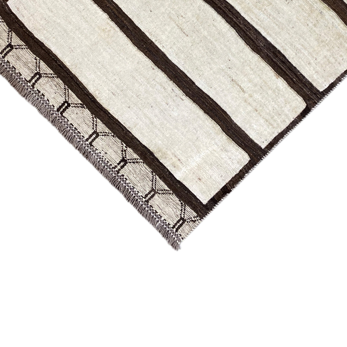 Corner of the Nimbaft rug with brown stripes and an embroidered decorative fringe border
