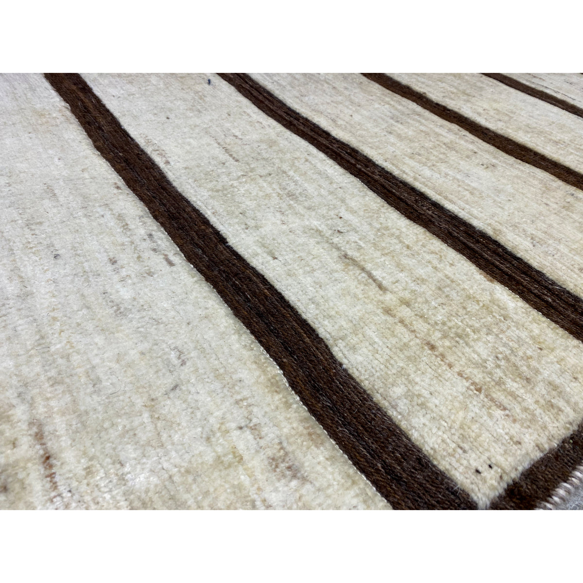 Detail of the Nimbaft rug: woven texture with beige areas and brown stripes