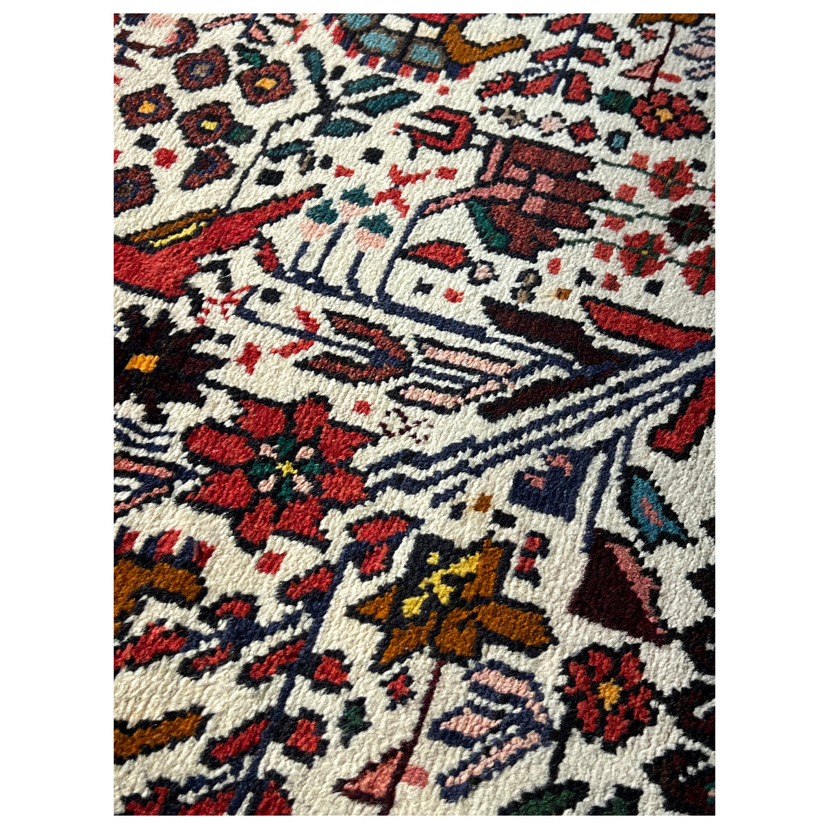 Poshti rug detail, dense ornamental pattern in cream, red, and blue