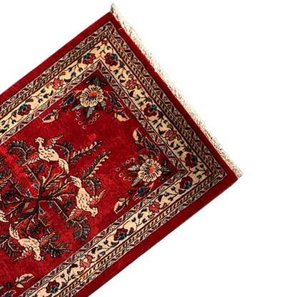 Detail of the red Poshti rug with an animal motif, floral ornaments, and a cream-colored border