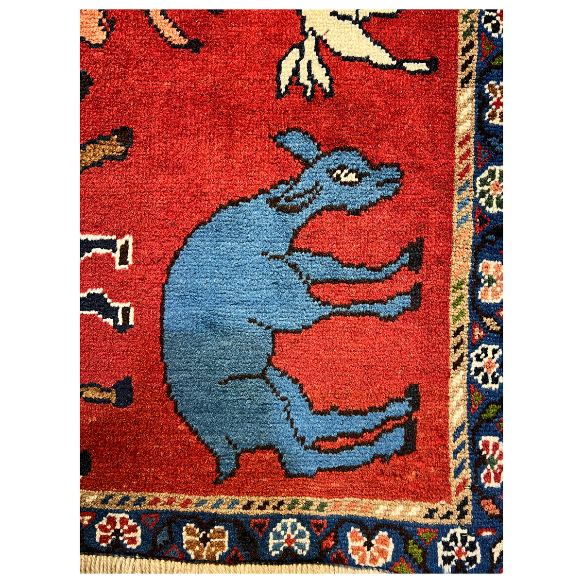 Wool rug with a red field, blue animal motifs, and an ornate side border