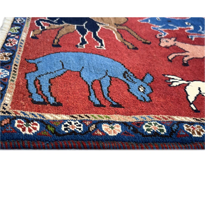 Wool carpet detail: red area with blue and brown animals and decorative border