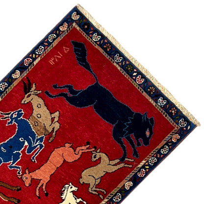 Wool rug detail view: red field with a dark blue animal, blue-and-gold border