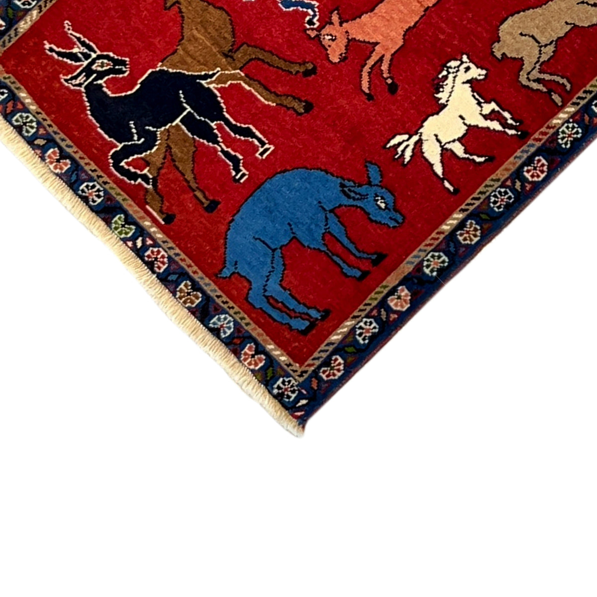 Wool rug detail view: red area with white, blue, and brown animal figures