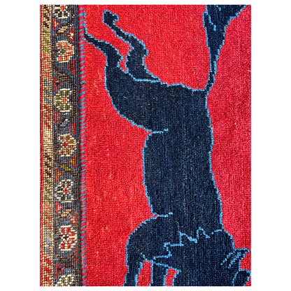 Wool carpet detail: red background with a dark animal figure and decorative side border