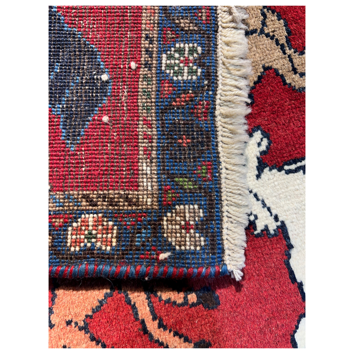 Wool rug detail at the fringe and border edge, red field with animal ornamentation