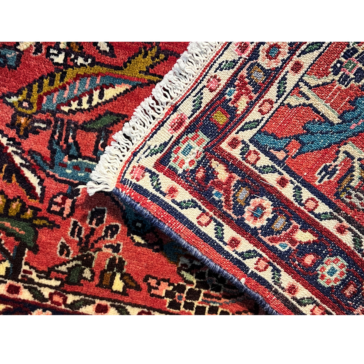 Poshti rug corner with fringes, red-blue pattern, and bound edge