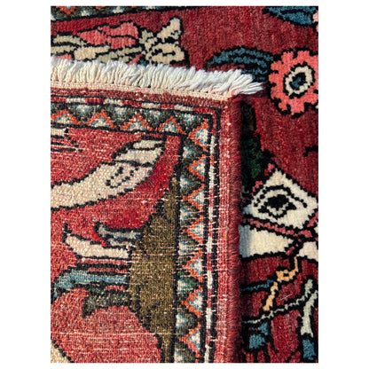 Detail of the carpet edge with fringes and colorful ornaments on a red patterned section