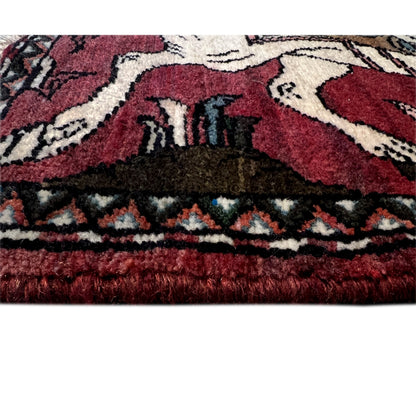 Bottom edge of a red Hamedan rug with a woven pattern and fringed trim