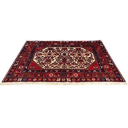 Rectangular red rug with a delicate pattern, dark borders, and light fringes