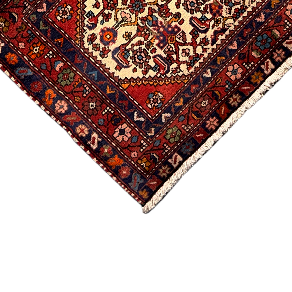 Close-up of carpet edge: red pattern with dark blue stripes and light borders
