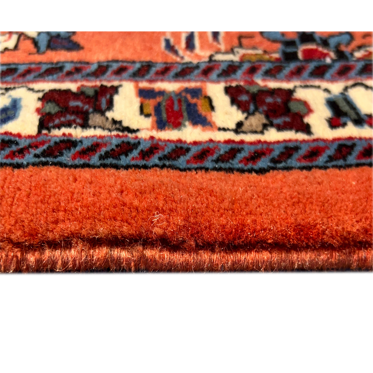 Carpet edge in detail: orange pile with a bordered pattern and dark edge