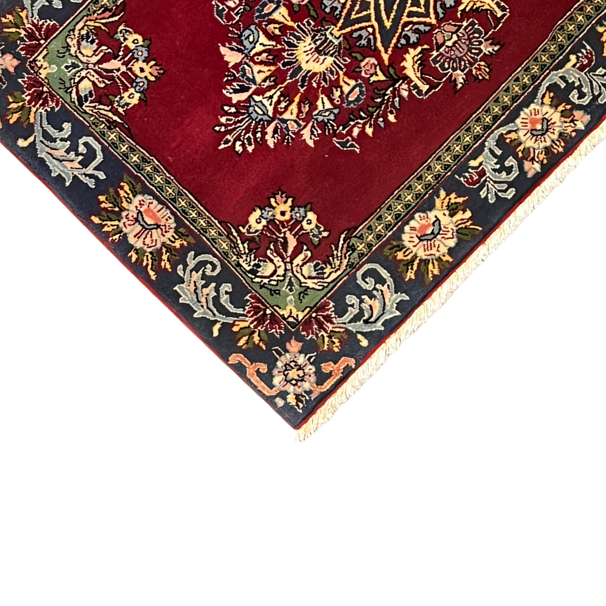 Top-down view of a carpet corner: red patterned field with a decorative border in blue and gold