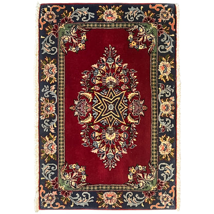Red rug with an ornamental pattern and dark border, rectangular, with fringes