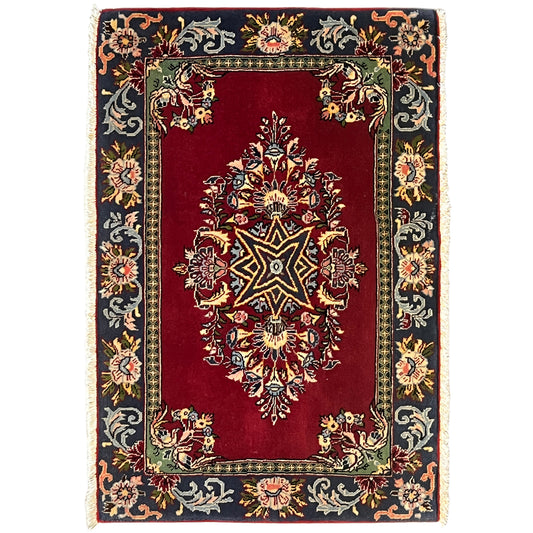 Red rug with an ornamental pattern and dark border, rectangular, with fringes
