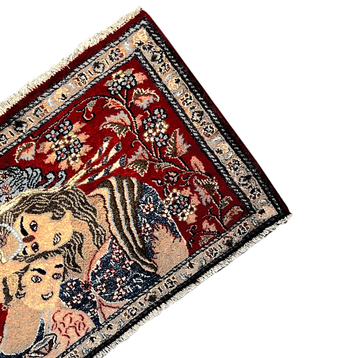 Corner of a red rug with fringes and an intricately detailed decorative border