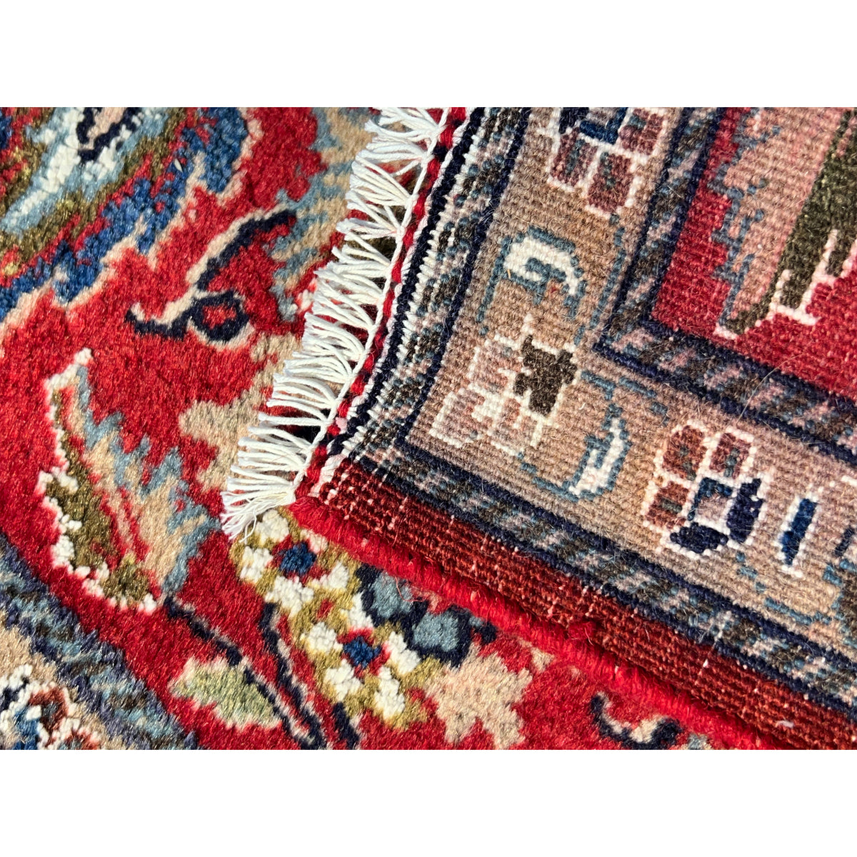 Fringes and patterned detail along the edge of a red ornamental rug