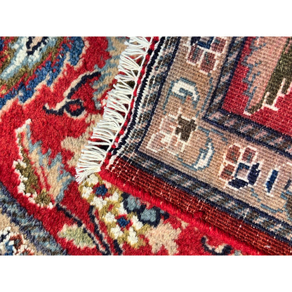 Fringes and patterned detail along the edge of a red ornamental rug