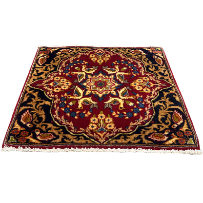 Square rug with a red border design, dark blue background, and fringes