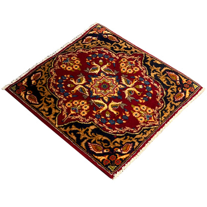 Square rug with a twisted look: red center, blue-and-gold ornaments, fringe